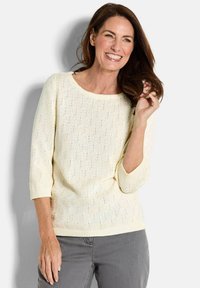 Strickpullover in sanftem Creme mit einem strukturierten Muster und Dreiviertelärmeln. Das gerippte Hals- und Saum gibt dem Pullover eine klare Definition.