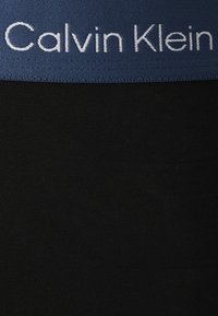 Zwarte stoffen shorts met een brede blauwe elastische tailleband met het "Calvin Klein" logo in witte borduring. Gladde textuur, aansluitend ontwerp.