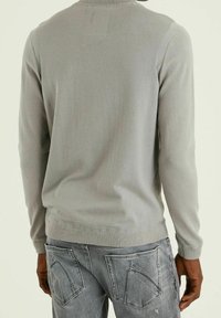 Pull en maille gris clair à manches longues avec un col rond. Le tissu est lisse, et la coupe est standard avec des poignets et un ourlet côtelés.