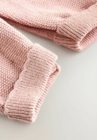 Rosa, gestrickte Pulloverkombinationen mit geripptem Muster, die ein gewebtes Design und weichen, gemütlichen Stoff bieten. Die Kanten sind ordentlich verarbeitet.