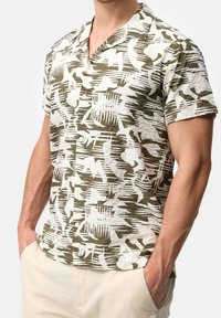 Kurzärmeliges Hemd in Off-White und Olivgrün mit einer strukturierten Stoffqualität und einem Muster aus Blättern und abstrakten Formen. Design mit Knopfleistenkragen.
