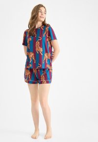 Piżama z krótkim rękawem, charakteryzująca się fioletowo-szaroniebieskim wzorem w paski z pomarańczowymi tygrysami. Szorty mają elastyczny pas i luźny krój.
