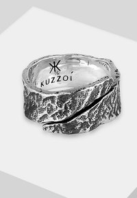 Sterling silver ring with a textured, rocky surface and a twisted design. Marked with the logo "Kuzzoi" inside.