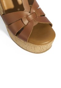 Sandale plateforme en cuir marron avec un design de lanière tressée et une semelle en liège, dotée d'un orteil arrondi et d'un semelle intérieure texturée.