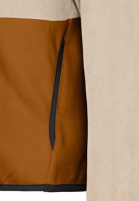 Λεπτομέρεια δίχρωμης φλις ενδυμασίας με μπεζ και καφέ πάνελ υφάσματος και κάθετη τσέπη με μαύρο περίγραμμα στην καφέ περιοχή.