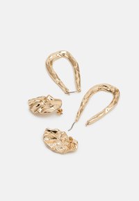 Pendientes en tono dorado que presentan dos aros abstractos y un diseño de hoja texturizada. Superficies lisas con un acabado martillado.