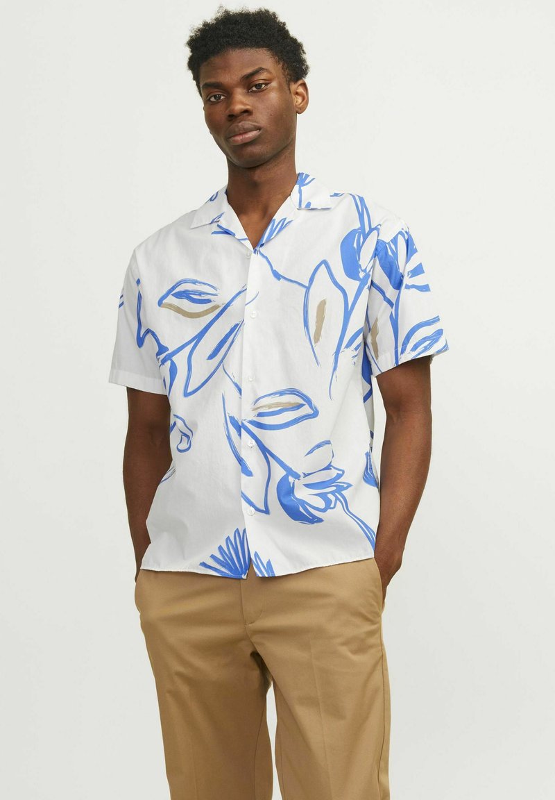 Camisa de manga corta en tejido blanco con patrones florales azules y beige, con un cuello relajado y cierre de botones.