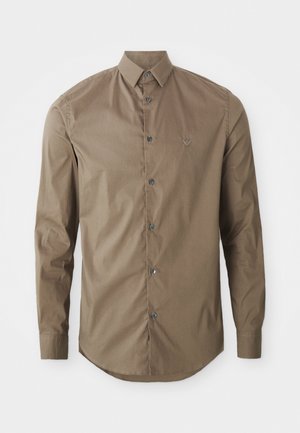 Chemise marron à manches longues en tissu lisse, avec un devant à boutons et un col pointu. Détail de petite broderie sur la poitrine.