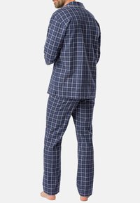 Ensemble de pyjama à carreaux bleu marine en tissu doux, comprenant un haut à boutons et un pantalon assorti avec une taille élastique.