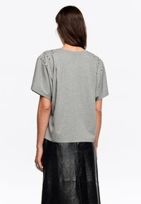 Szary T-shirt z krótkim rękawem o luźnym kroju, z ozdobnymi ćwiekami na ramionach i gładką, miękką fakturą.