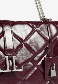 Borsa a tracolla in pelle trapuntata di un lucido bordeaux scuro, con catena argentata, chiusura con logo "VL" in argento e piccolo dettaglio lucchetto argentato.