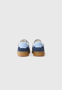 Navy og lyseblå ruskinds sneakers med en gummisål, der har hvide detaljer og et logo på hælen. Runde tå og polstret krave.