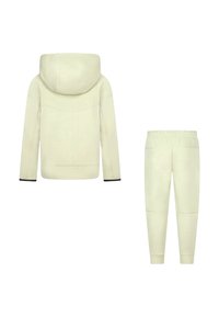 Felpa con cappuccio color crema con cappuccio ampio e pantaloni jogger abbinati con vita elastica e polsini stretti, mostrati di spalle.