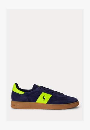 Sneaker in camoscio blu navy con striscia laterale e linguetta sul tallone di colore giallo neon, suola marrone, lacci e logo Polo Ralph Lauren sul lato.