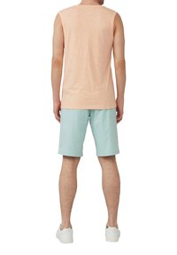 Hellrosa ärmelloses Top kombiniert mit mintgrünen Shorts, aus weichem Stoff gefertigt. Weiße Sneaker runden das lässige Outfit ab.