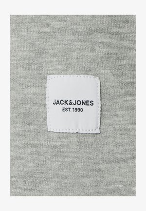Szürke anyag, kötött textúrával, fehér szőtt címkével, rajta a "JACK&JONES EST. 1990" felirattal fekete betűkkel.