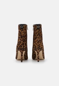 Botines con estampado de leopardo hechos de un material texturizado tipo ante. Presentan una punta afilada y un tacón de aguja, acentuados con herrajes negros.