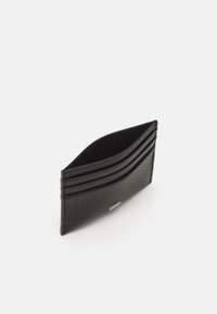 Portofel negru realizat dintr-un material texturat, cu linii curbate și detalii perforate. Design compact cu mai multe sloturi pentru carduri pe partea din față.