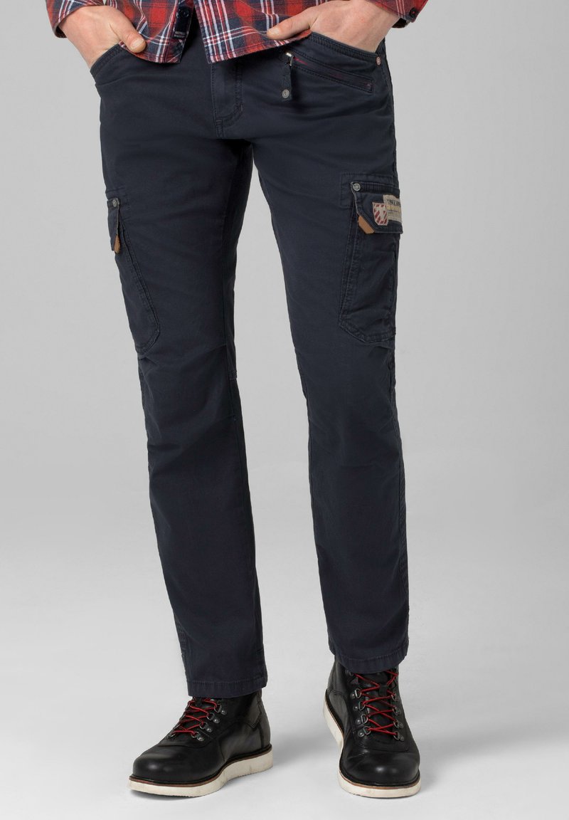 Navy cargo pants made from durable fabric feature multiple pockets, textured accents, and a tapered fit, paired with black boots and red laces.
