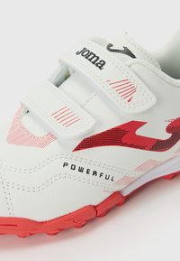 Hvit sportsko med røde detaljer, borrelåsrem, teksturert overdel og "POWERFUL" trykt på siden. Designet for sportsbruk.