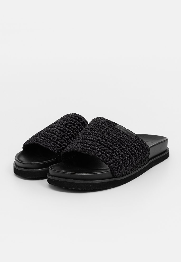 Czarne klapki z tkaninowym wierzchem i gładką syntetyczną podeszwą. Płaski design, szeroki pasek i teksturowana powierzchnia na pasku.
