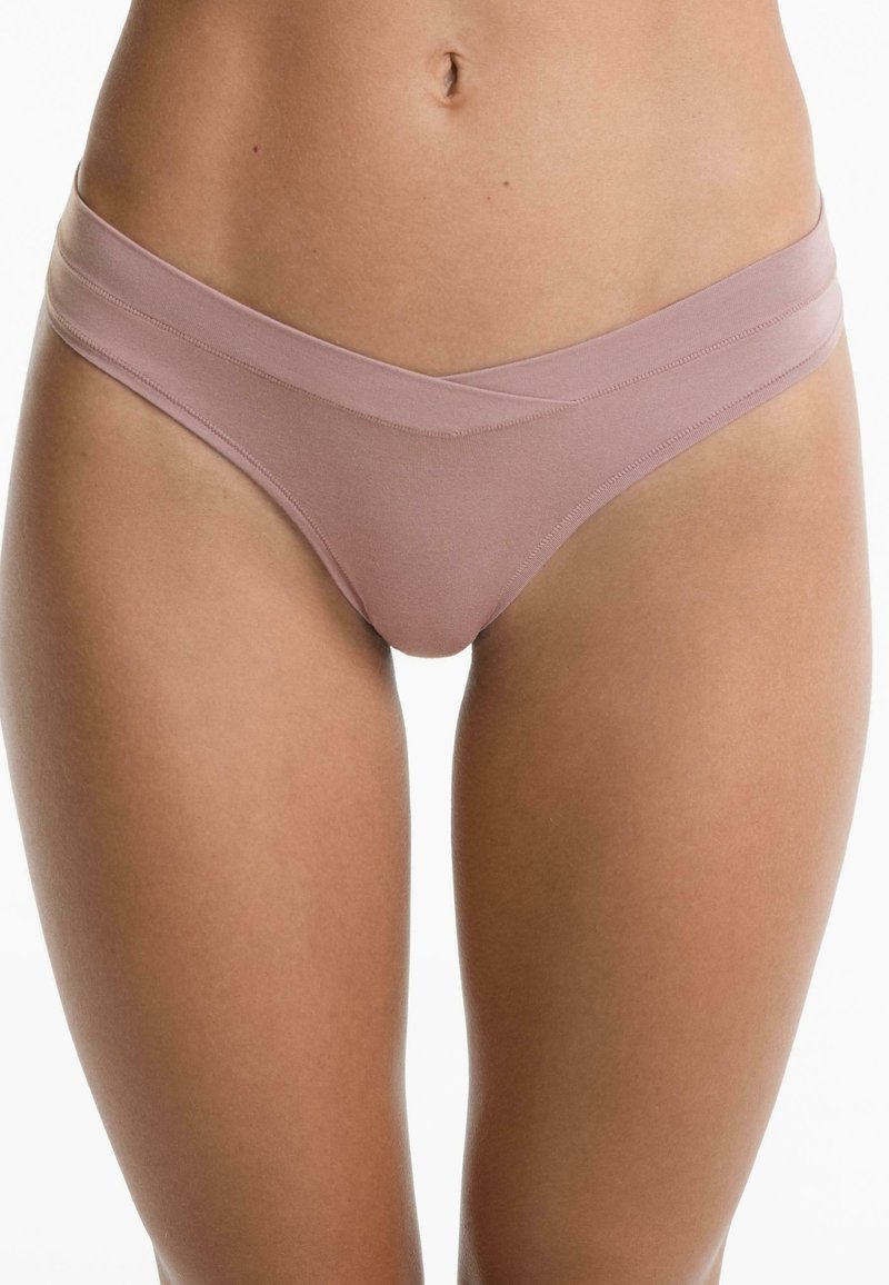 Dunne, naadloze roze bikini-slip met een hoge, overlappende taillebandontwerp. Gemaakt van zachte, rekbare stof en heeft een minimalistische snit.