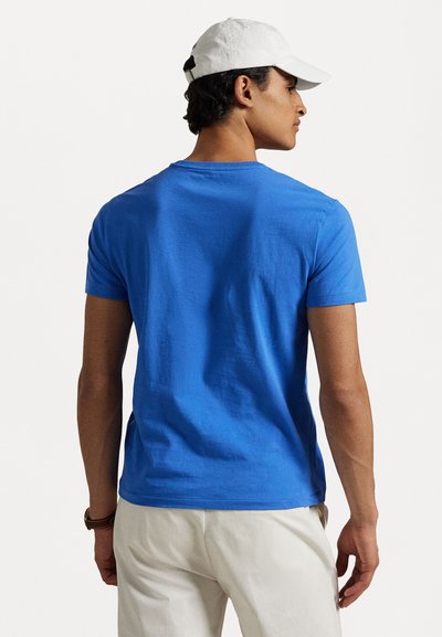 Kungsblå t-shirt med rund hals i bomull, med korta ärmar och normal passform, bärs med krämfärgade byxor.