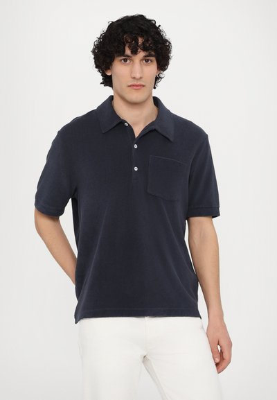 Marinblå polo t-shirt i mjukt tyg, med knäppning fram, korta ärmar och en bröstficka. Ren och minimalistisk design.