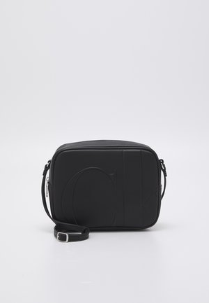 Sac bandoulière rectangulaire noir avec sangle réglable et grand logo "CK" embossé sur une surface lisse.