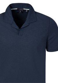 Polo azul marino de manga corta con cuello abierto y pequeño detalle de rayas verdes y blancas en el interior del escote.