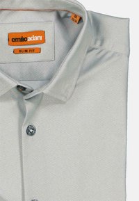 Schmal geschnittenes Hemd in hellem grauen Fischgrätenmuster, mit weicher Textur, grauen Knöpfen und einem orangefarbenen Markenlabel im Kragen.