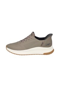 Zapatilla deportiva de color marrón claro con una parte superior texturizada y transpirable, diseño de cordones y una mediasuela de espuma blanca en contraste. Suela exterior de goma estriada.