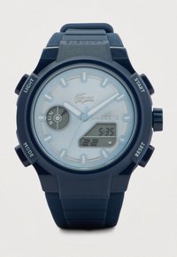 Montre-bracelet Lacoste bleue avec affichage analogique et numérique, indicateur de jour, et boutons étiquetés Lumière, Mode, Démarrer et Réinitialiser.