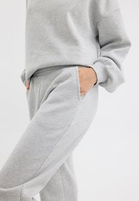 Grå bomullströja och matchande sweatpants med sidofickor, med en avslappnad passform och mjuk textur.