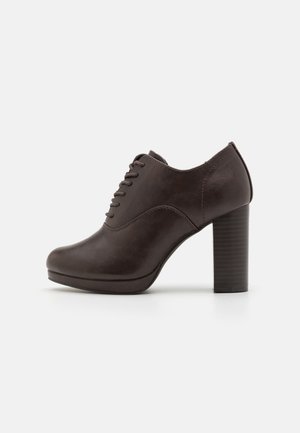 Donkerbruine leren veterschoen voor dames met een stevige blokhak en een ronde neus, weergegeven in profiel op een witte achtergrond.