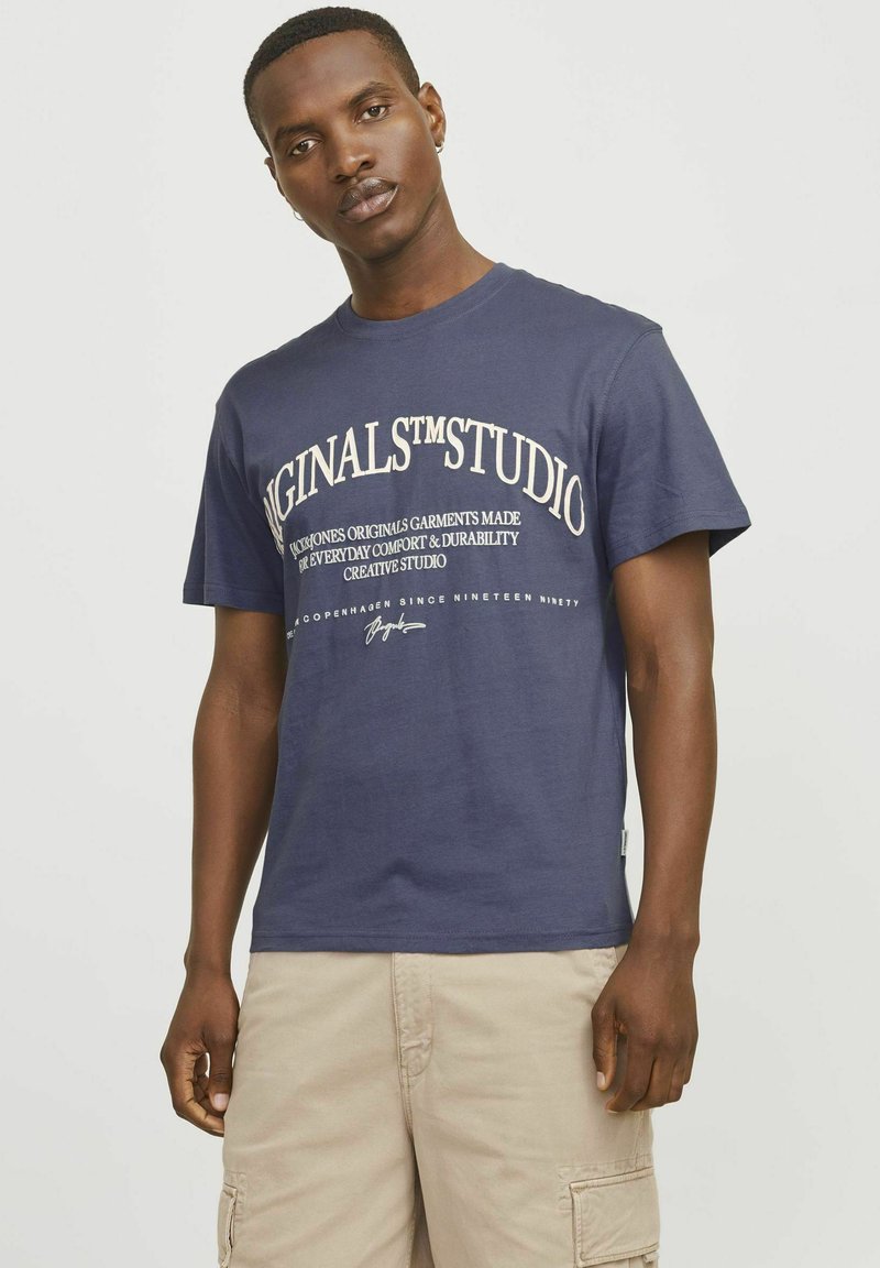 Marineblauwe katoenen t-shirt met korte mouwen, voorzien van witte tekstgraphics aan de voorkant. Ronde hals en een effen ontwerp zonder patronen.