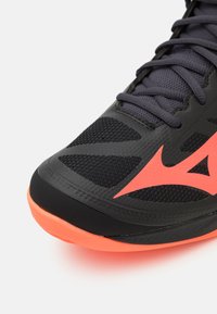 Schwarzer Sportschuh mit einem Mesh-Obermaterial und strukturierten Mustern, leuchtend orangefarbenen Akzenten und einer flexiblen Gummisohle.