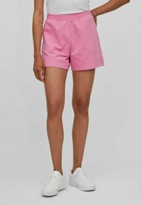 Rosa bomullsshorts med elastisk midjeband, har en avslappnad passform och sidofickor, i kombination med vita sneakers för kontrast.