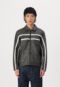 Black faux leather jacket with a zip front, white stripes across the chest and sleeves, and side pockets. Smooth texture, collared design.