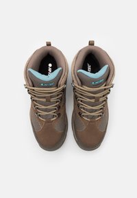 Brązowe i szare buty trekingowe z jasnobrązowymi sznurówkami oraz jasnoniebieskimi wyściełanymi mankietami, widoczne z góry na białym tle.