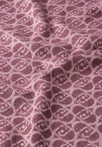 Tessuto caratterizzato da un motivo tessuto ripetuto in rosa scuro su uno sfondo rosa chiaro, con un aspetto morbido e leggermente strutturato.
