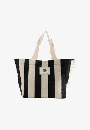 Tragetasche mit vertikalen schwarzen und beigen Streifen, beigen Griffen und einem rechteckigen Patch mit einem Sonnenlogo und dem zentrierten Schriftzug "self studios".