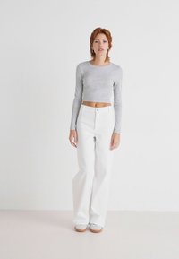 Witte wijde broek in combinatie met een grijze cropped longsleeve top, met een geribbelde textuur en een getailleerd silhouet. Eenvoudig ontwerp, minimale details.