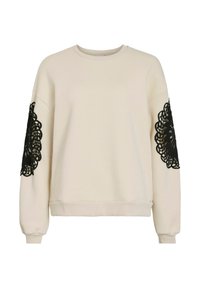 Cream sweatshirt featuring long sleeves with black lace details. Smooth fabric with a round neckline and ribbed cuffs and hem.