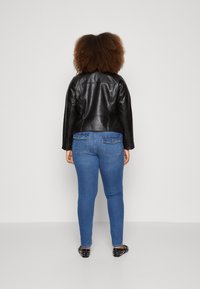 Svart läderjacka, figursydd design; blå skinny jeans med bakfickor; texturerad tyg; svarta ballerinas med nitar.