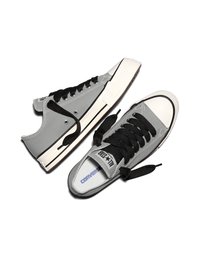 Par de zapatillas Converse All Star bajas en gris con cordones negros, punteras de goma blancas y medias suelas blancas con rayas negras.