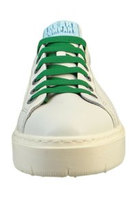 Zapatilla blanca con cordones verdes, una lengüeta texturizada azul, ojales circulares y una suela blanca gruesa. Material de cuero con detalles de costura.