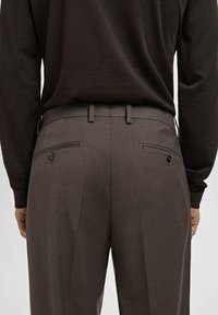 Pantalones marrones a cuadros con una textura suave, que cuentan con dos bolsillos traseros, parte delantera plana y un corte entallado.