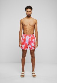 Pánske plavky s ružovým a svetlomodrým tie-dye vzorom, s elastickým pásom a zošitými čiernymi akcentmi.