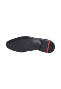 Semelle de chaussure en cuir noir avec surface texturée, bout légèrement arrondi et accent rouge sur le talon. Présente des détails de couture complexes.